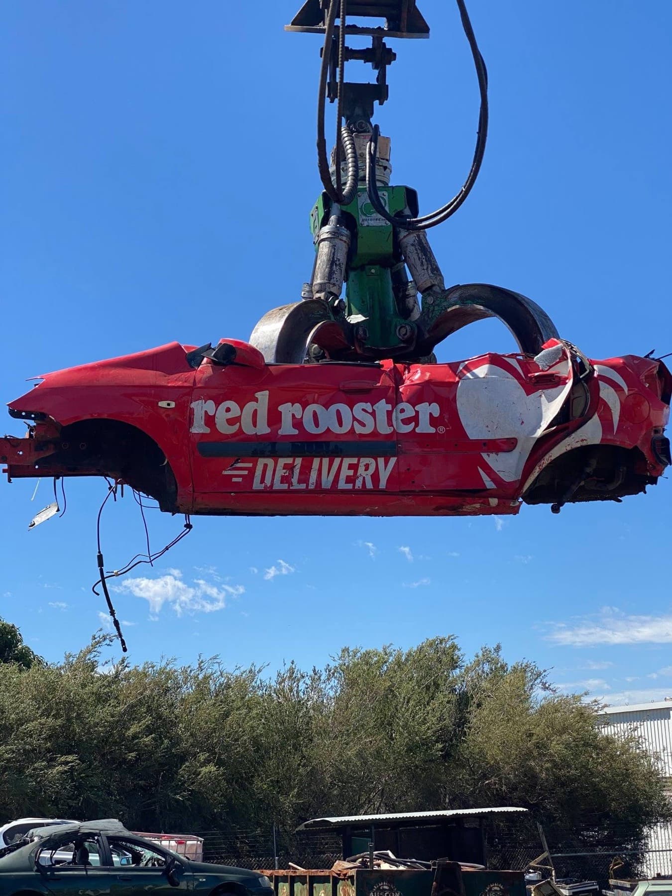 Scrap car body being lifted by a hydraulic grab at the yard